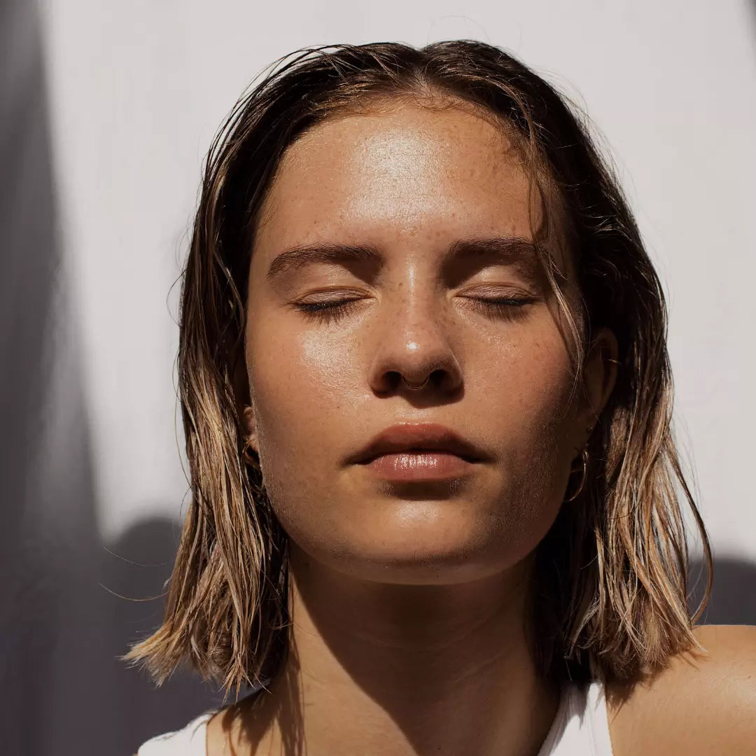 Femme qui prend le soleil avec sur son visage de la crème pour prendre soin de sa peau